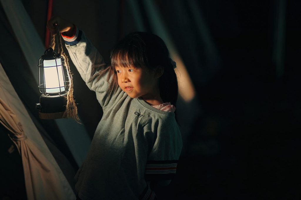 a girl with lantern outside at night while camping