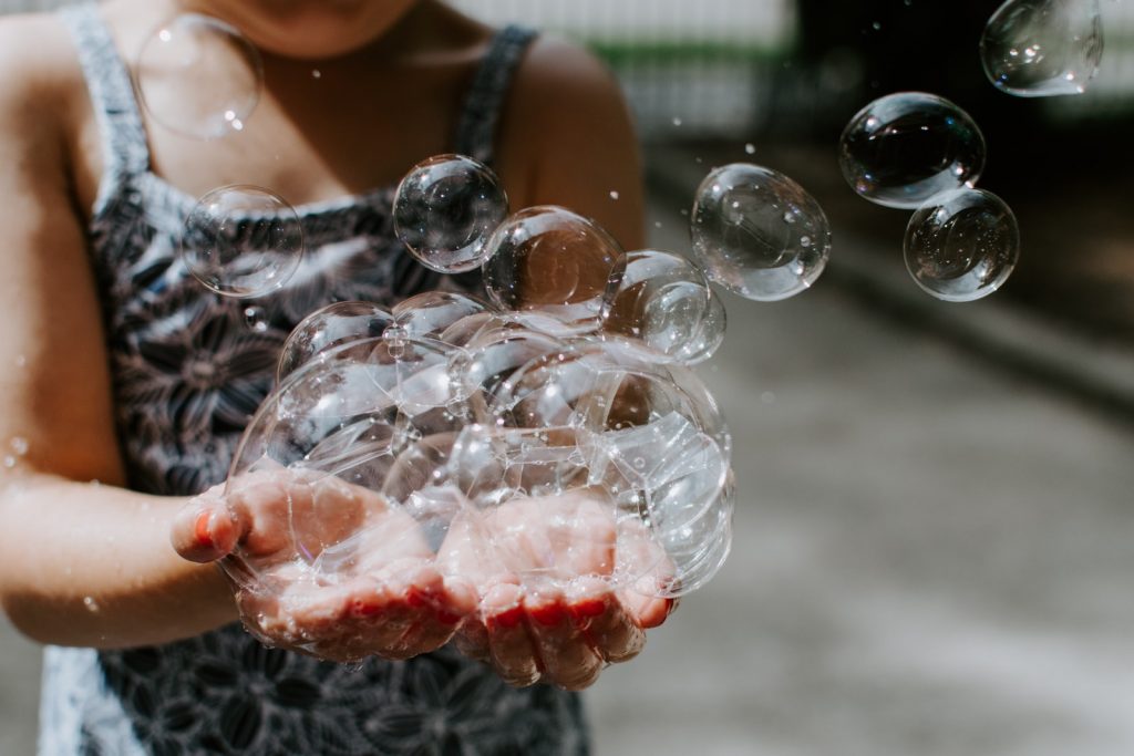 child holding soap bubbles outdoors