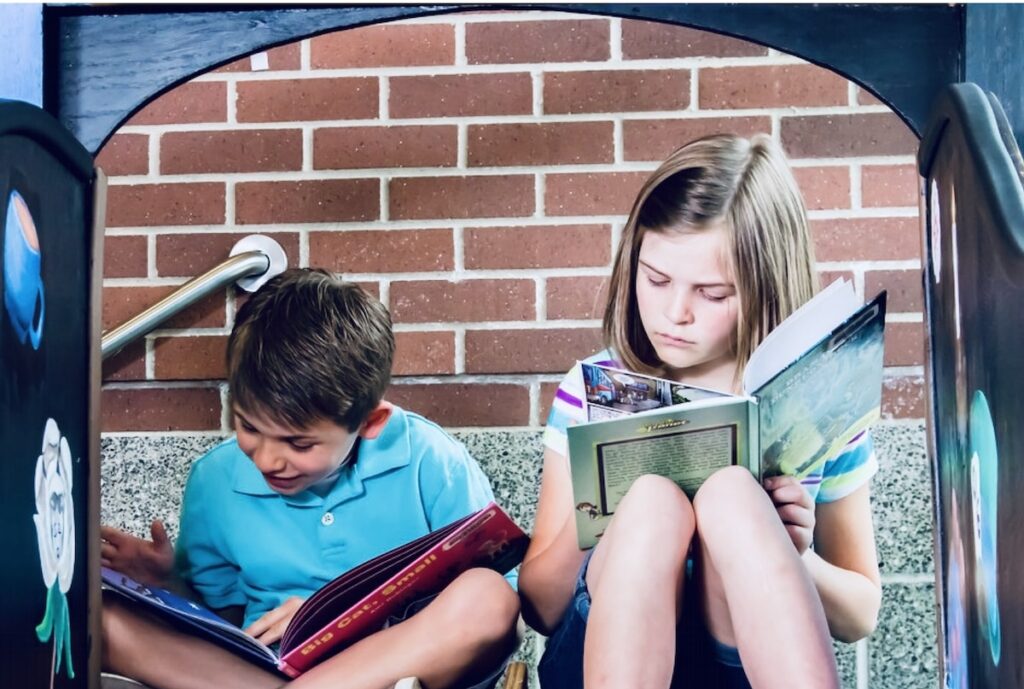 two kids sitting outside reading books