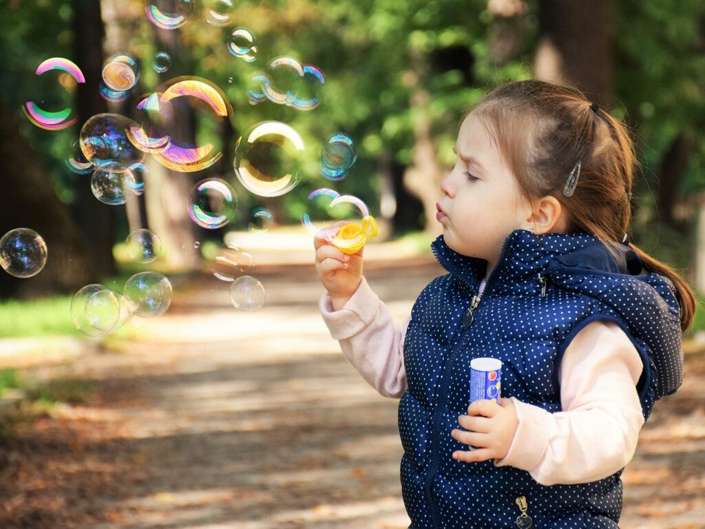 a toddler blowing bubbles outside