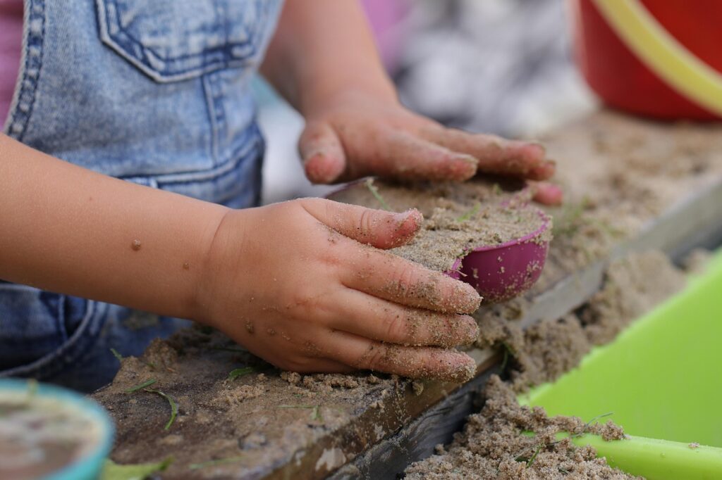 Toddler playing in the sand as a sensory activity for toddlers and preschoolers