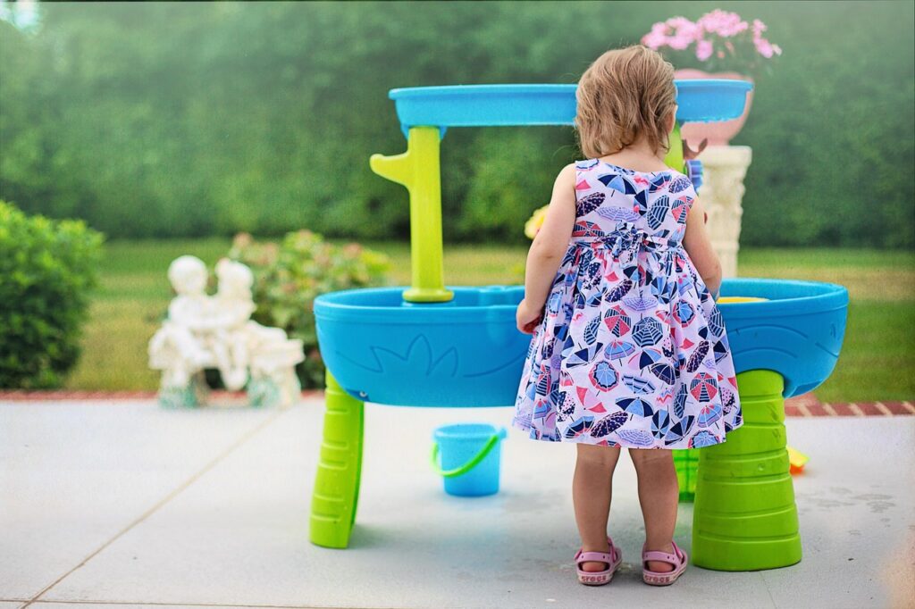 a girl playing at a water table outside